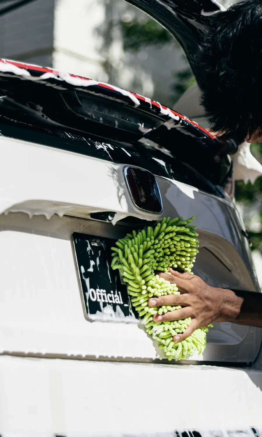 Detailer carefully finishing the rear of a white Honda